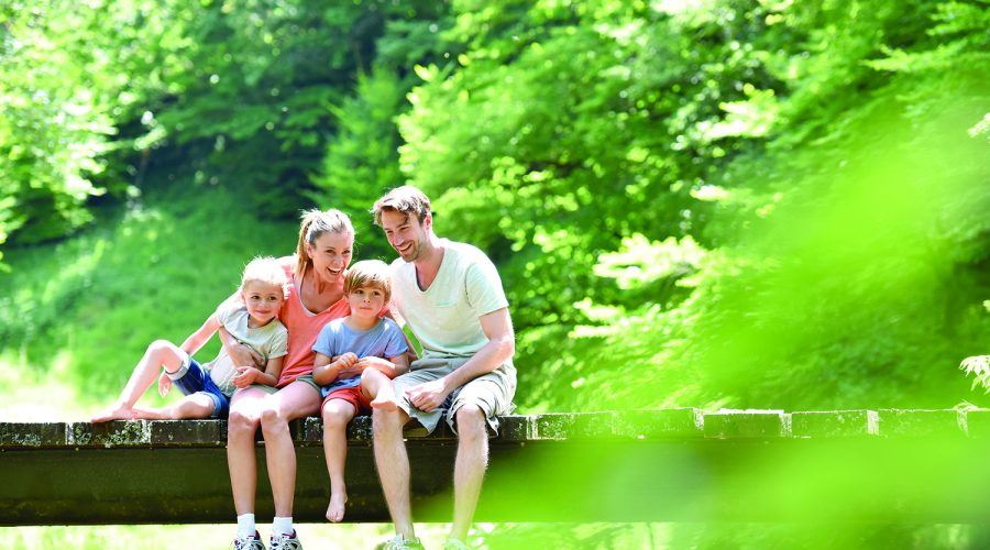 Family sitting on a bridge crossing mountain river